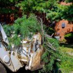 Tree removal equipment clearing a fallen tree in a residential yard.
